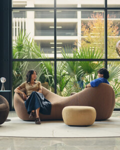 Two people seated on upholstered lounge sofa with ottoman in modern interior space